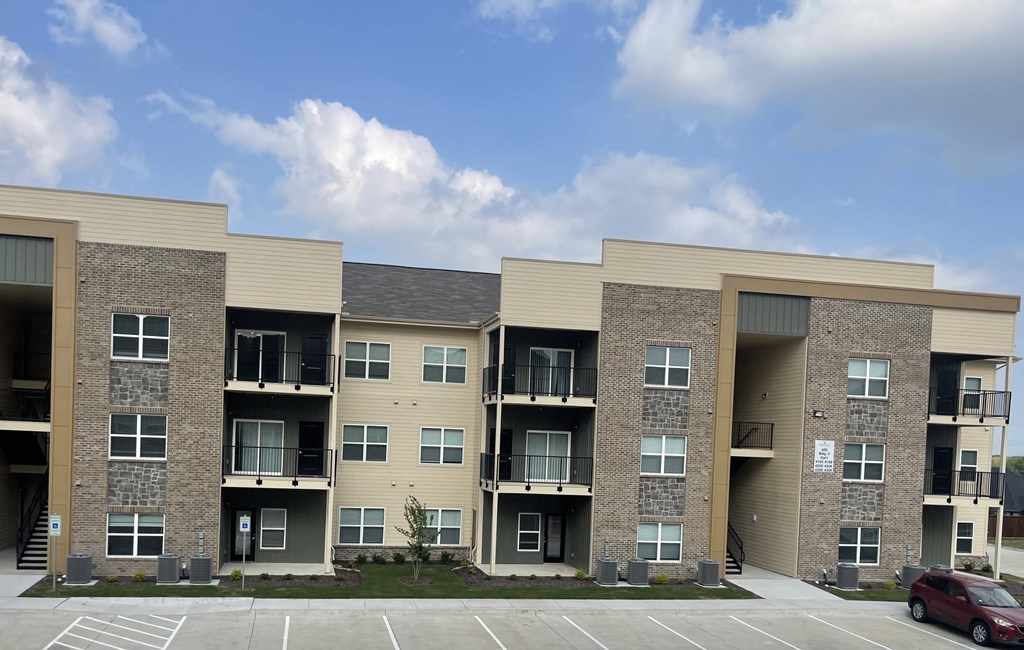 an exterior view of an apartment building with a car in a parking lot