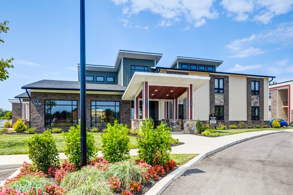 A modern house with a large front yard and a driveway.