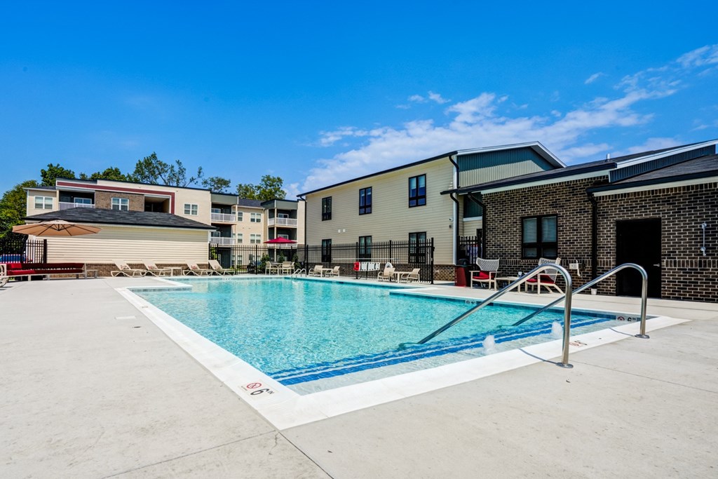 A swimming pool in front of a building with a blue sky in the background.