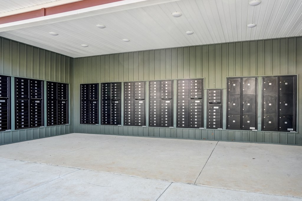 A wall of black lockers in a room with a concrete floor.