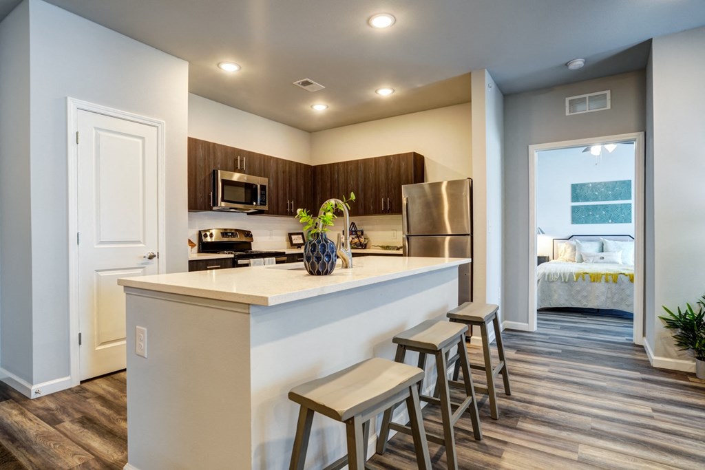 A kitchen with a white counter top and wooden floors.