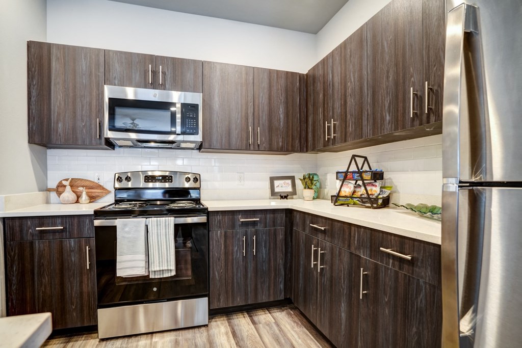 A modern kitchen with dark wood cabinets and stainless steel appliances.