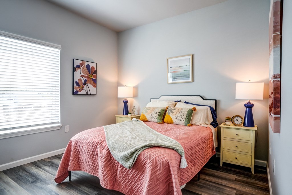 A bedroom with a bed, nightstands, and a window.