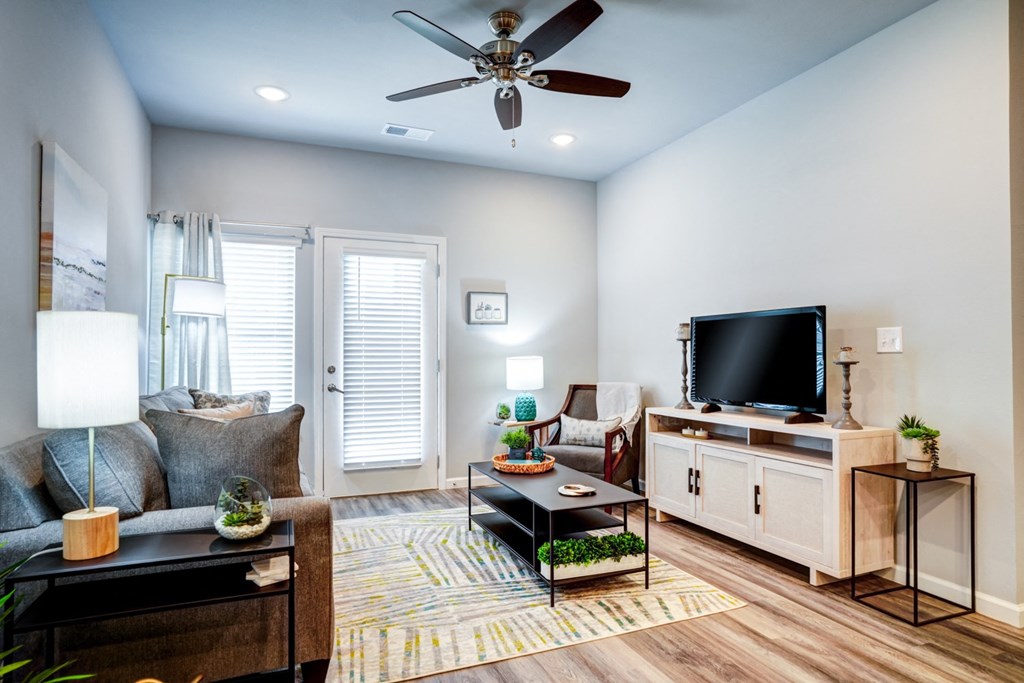 A living room with a ceiling fan, a couch, a coffee table, and a television.