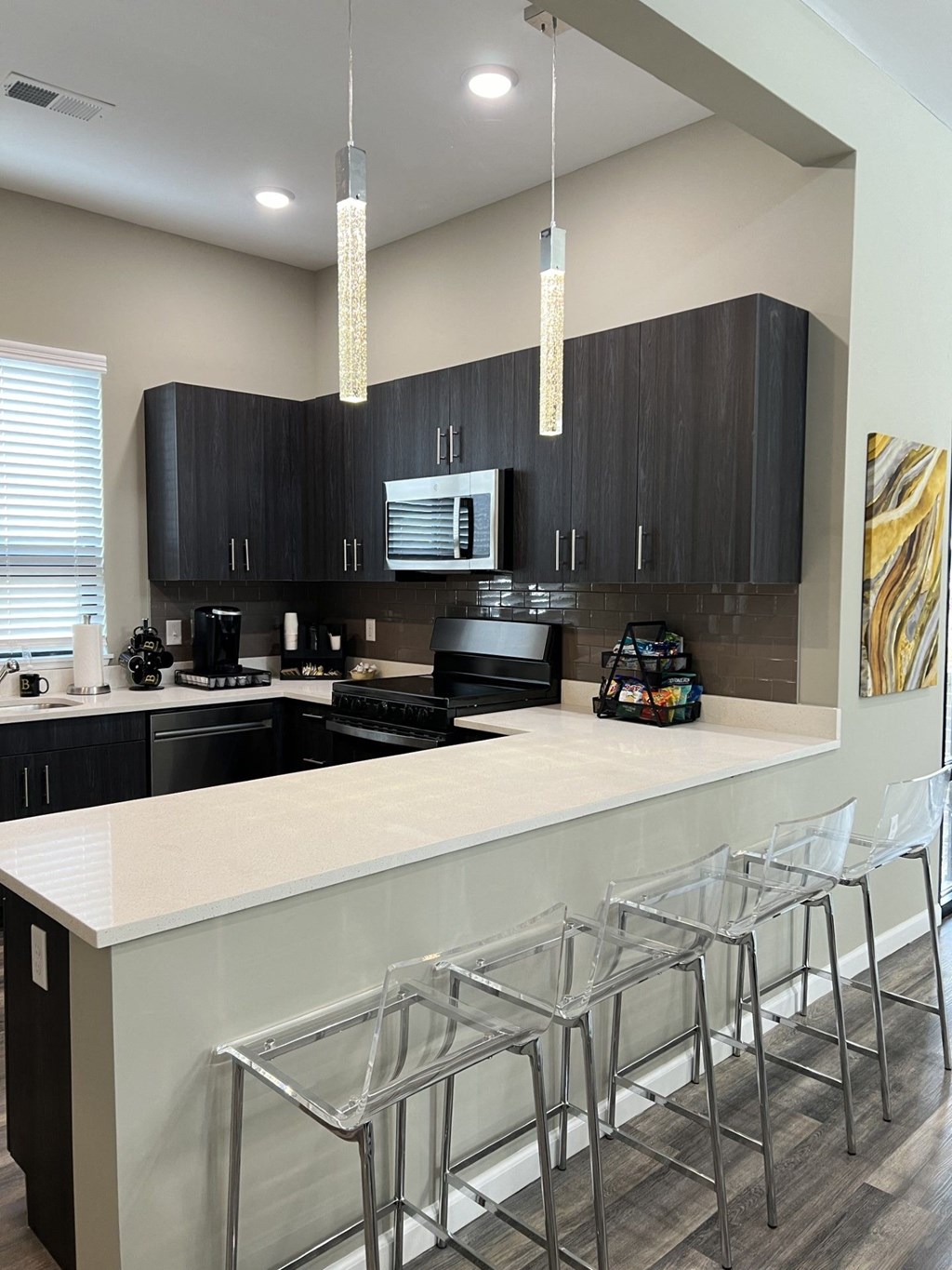 a kitchen with black cabinets and a bar with chairs