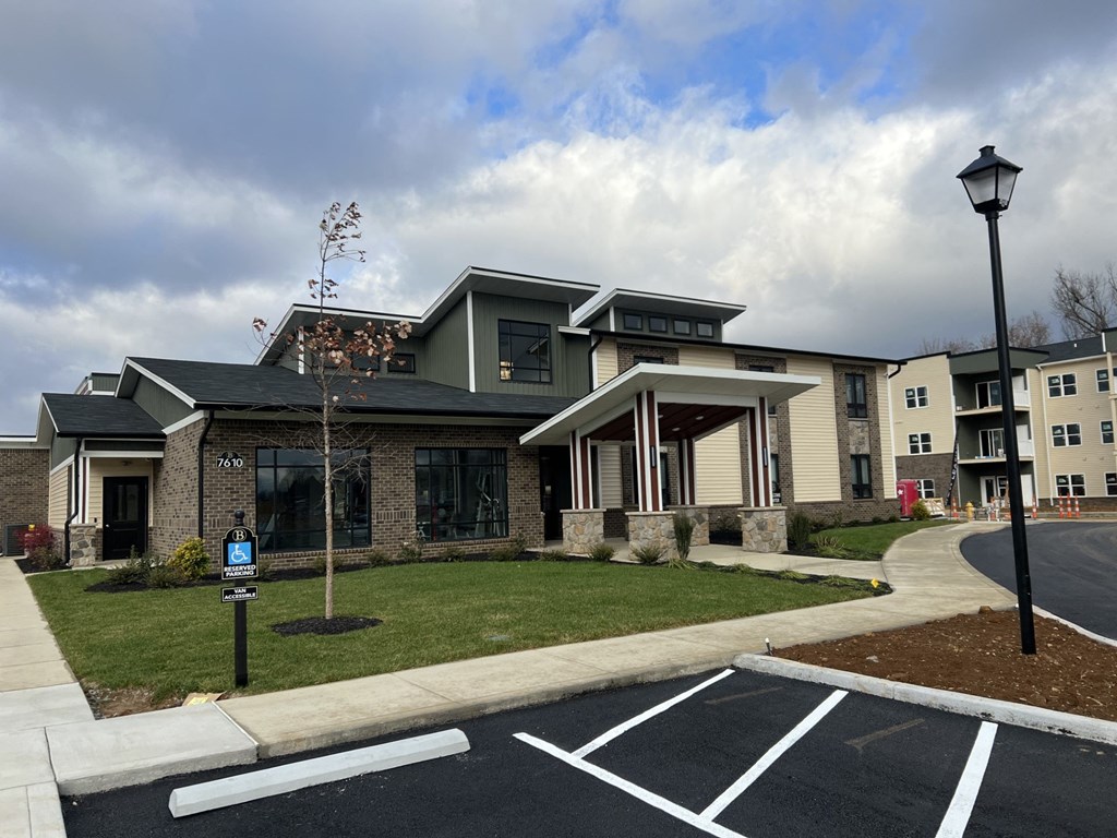 an apartment building with a lawn and a parking lot