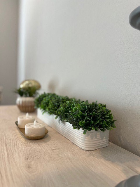 a vase with green plants on a table with candles