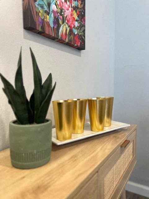 a plant and four gold cups on a table