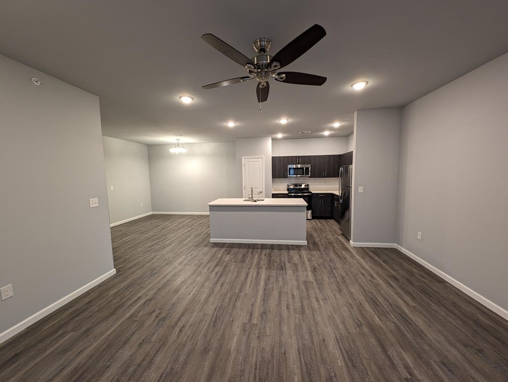 a living room with a kitchen and a ceiling fan