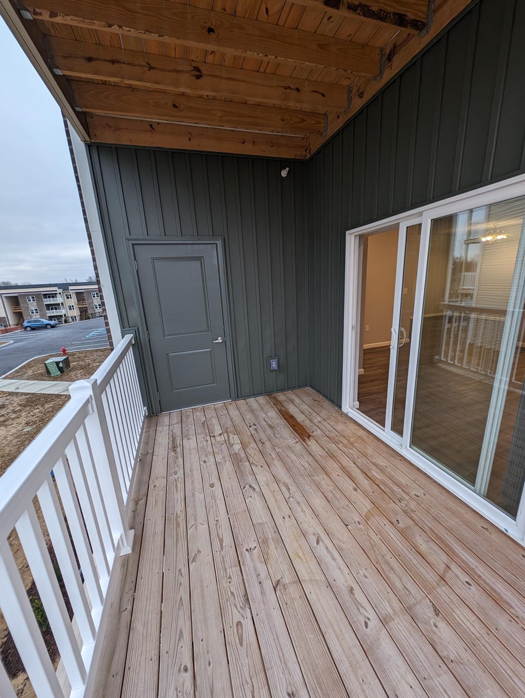 a porch with a wooden deck and a gray door