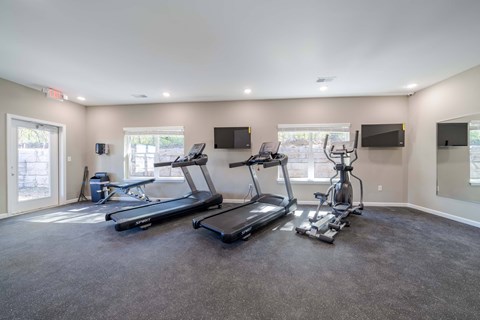 A spacious room with a treadmill, elliptical trainer, and stationary bike.