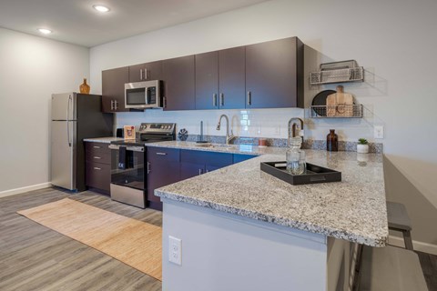 A kitchen with a granite counter top and stainless steel appliances.