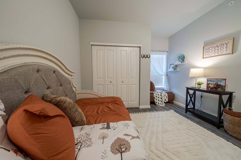 A bedroom with a large bed and a small table with a lamp.