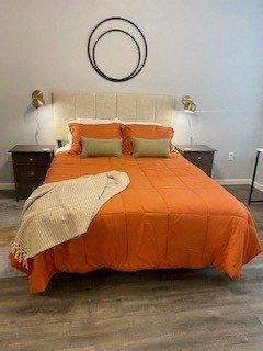 a bed with an orange comforter and orange pillows