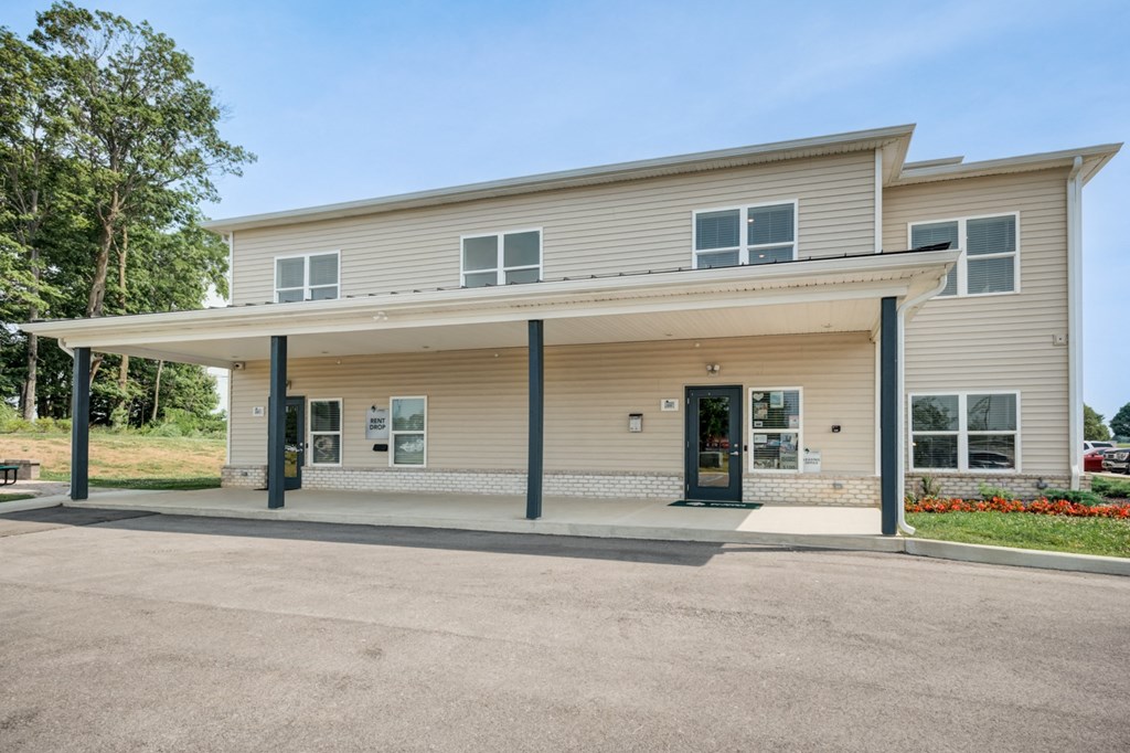 the front of a tan house with columns and a driveway