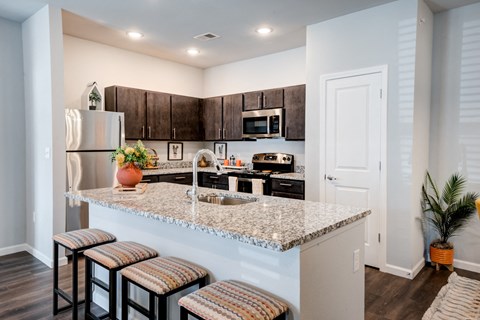 a kitchen with granite counter tops and a bar with stools