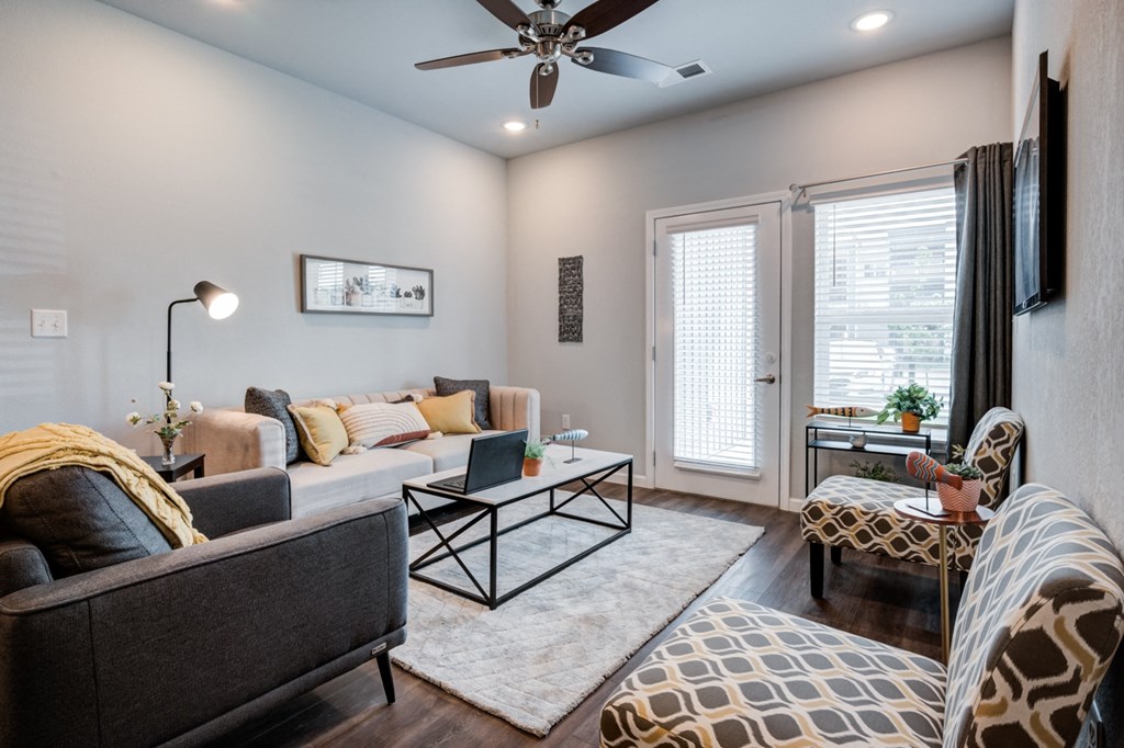 a living room with a couch and a chair and a ceiling fan