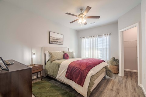 A bedroom with a bed, nightstand, and a ceiling fan.