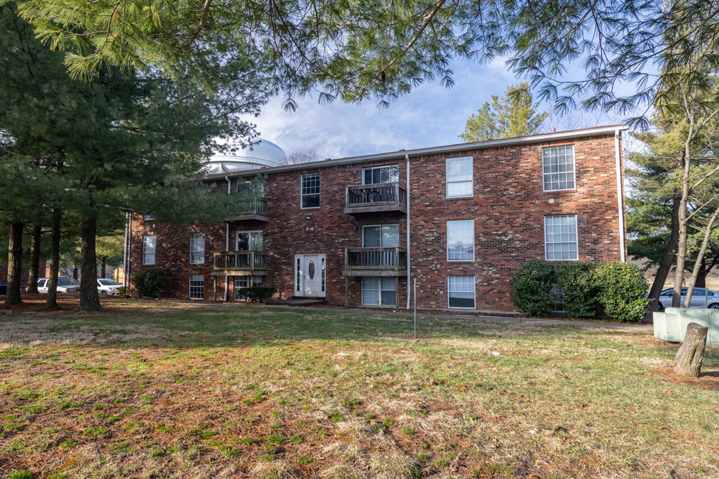 A brick apartment building with a green lawn in front.