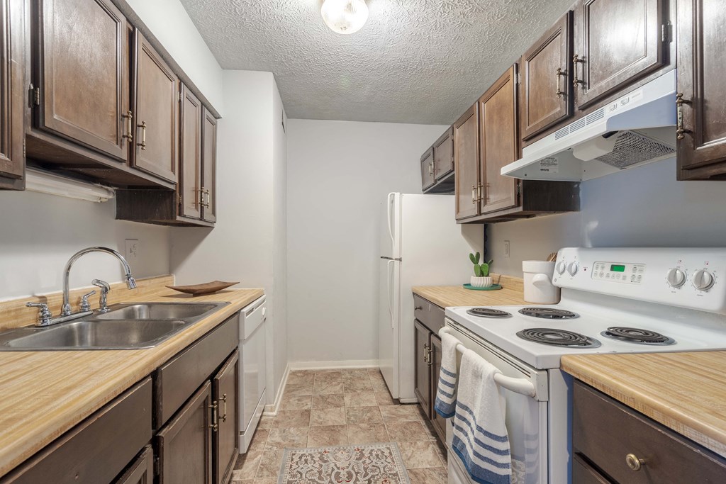 A kitchen with wooden cabinets and a white stove top oven.