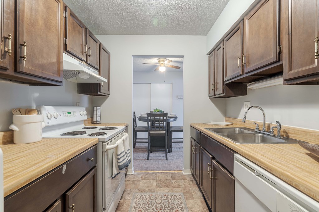 A kitchen with wooden cabinets and a white stove top oven.