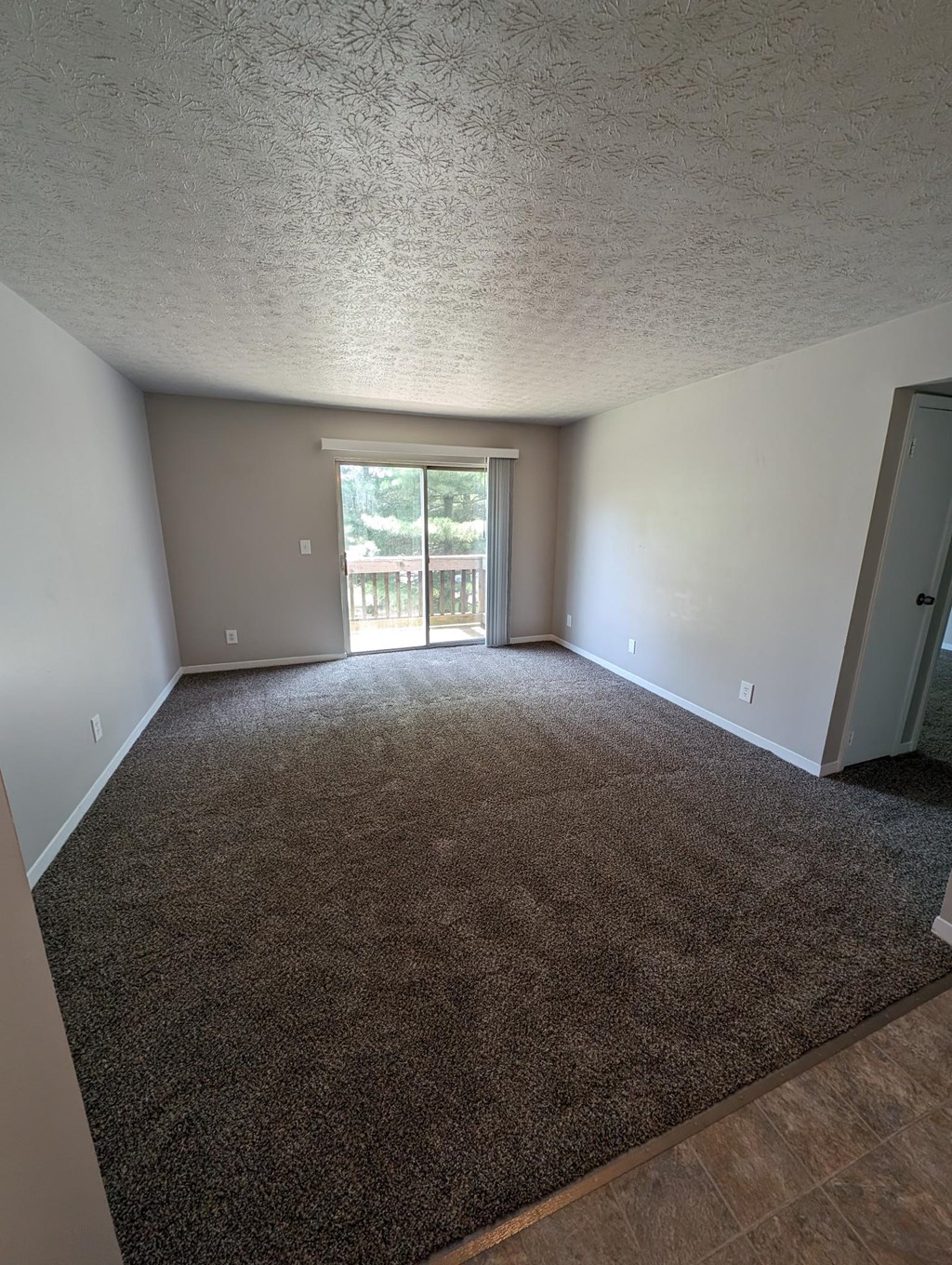 an empty living room with a door to a balcony
