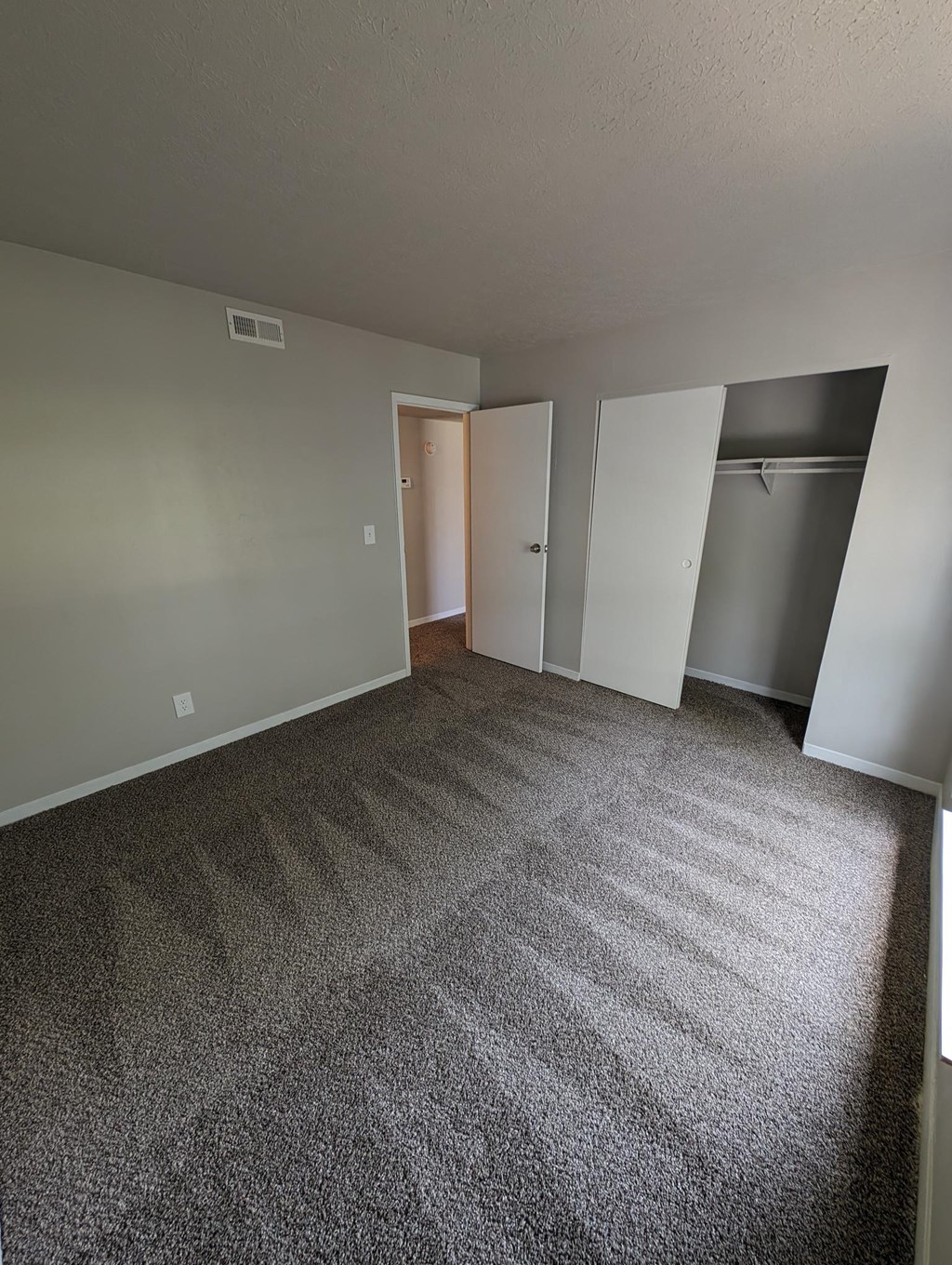 a bedroom with a carpeted floor and a closet