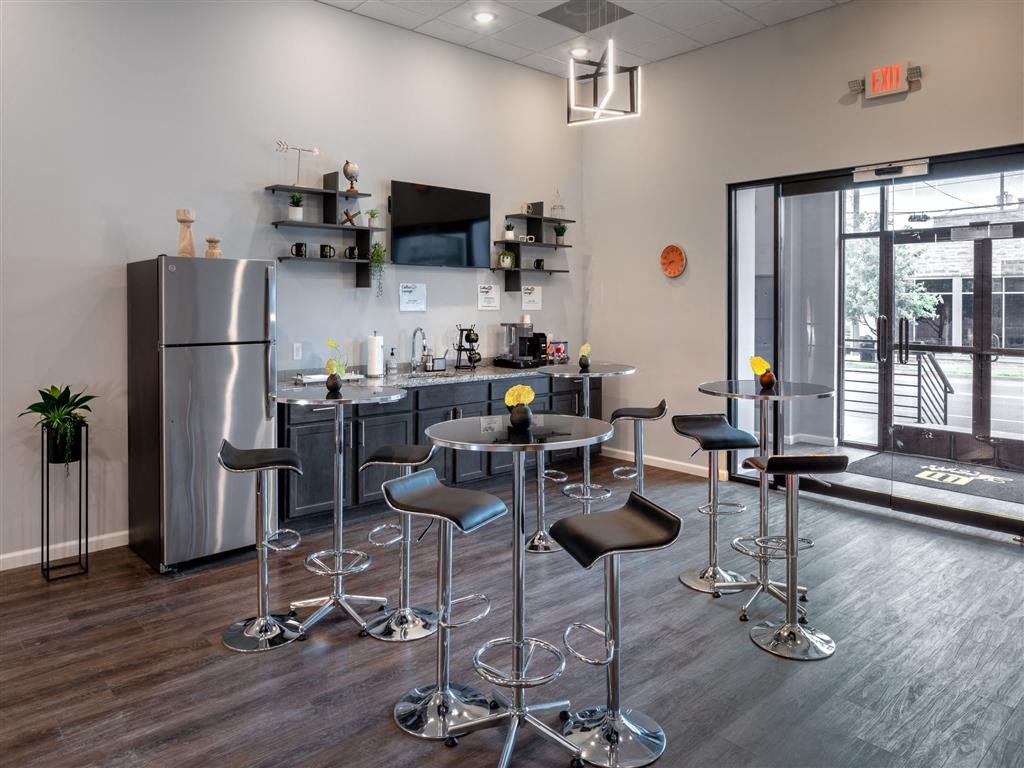 a kitchen area with bar stools and a counter with a refrigerator
