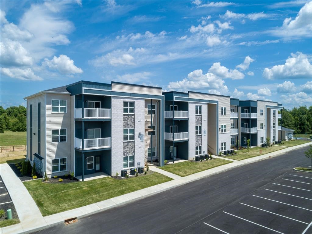 an exterior view of an apartment building with a parking lot