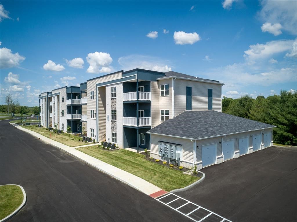 an exterior view of an apartment building with a road and grass