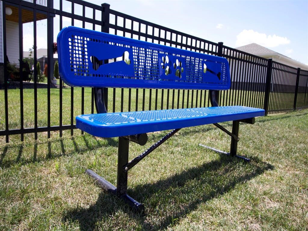 a blue bench in the grass in front of a fence