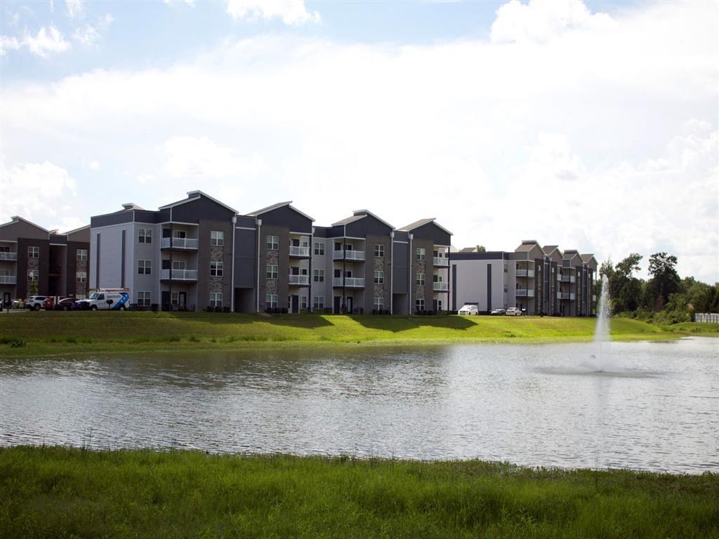 a pond with a fountain in front of an apartment building