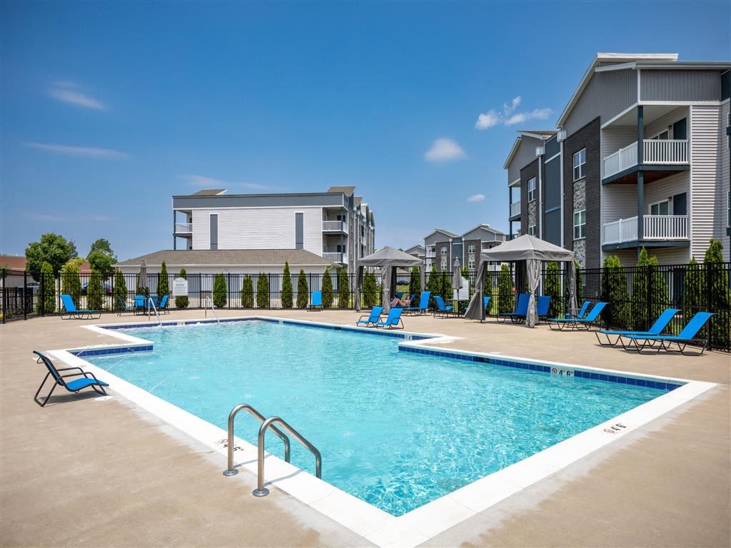 a resort style pool with blue chairs and a building in the background