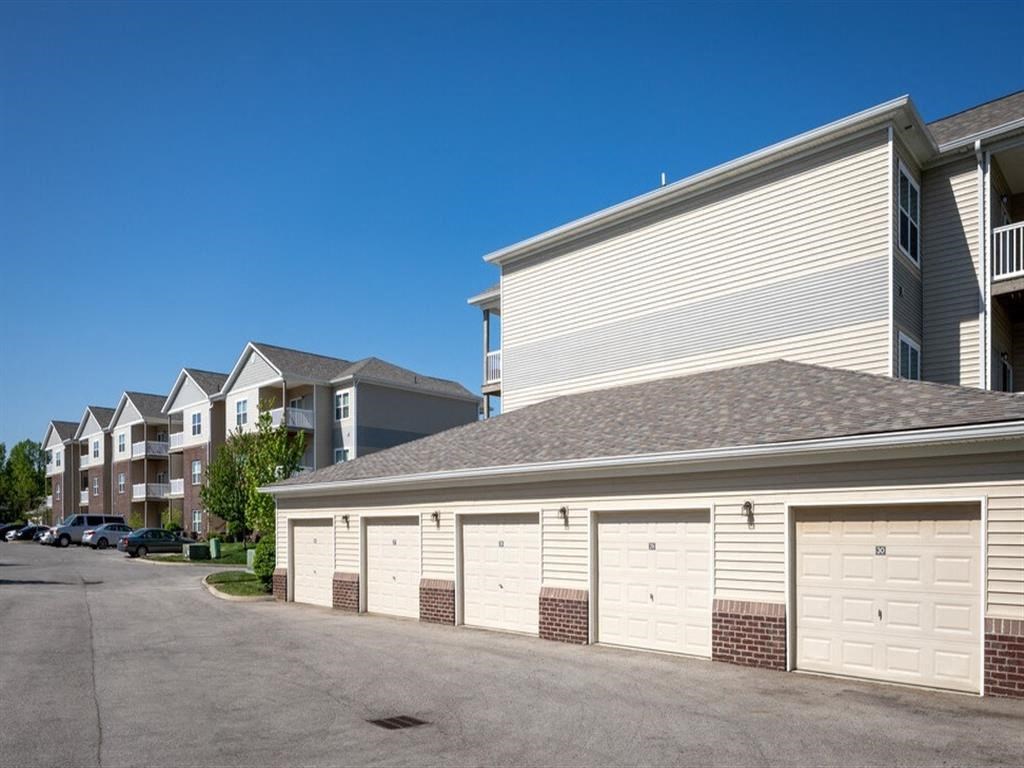 a building with white garage doors in front of some apartments