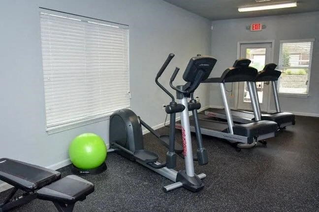 a gym with exercise equipment and a green ball