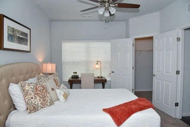 a bedroom with a large white bed and a ceiling fan