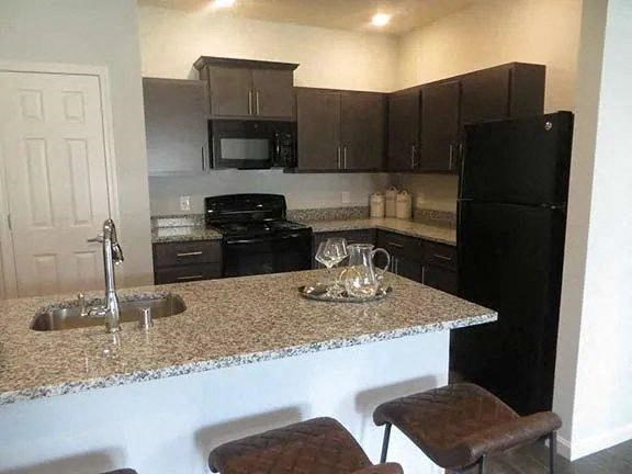 a kitchen with a granite counter top and a black refrigerator