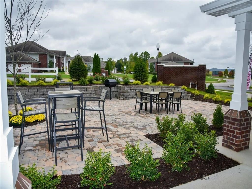 a patio with tables and chairs and a brick wall