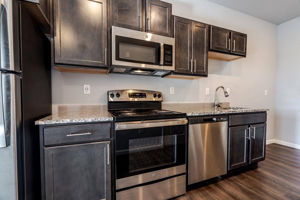 A modern kitchen with dark wood cabinets and stainless steel appliances.