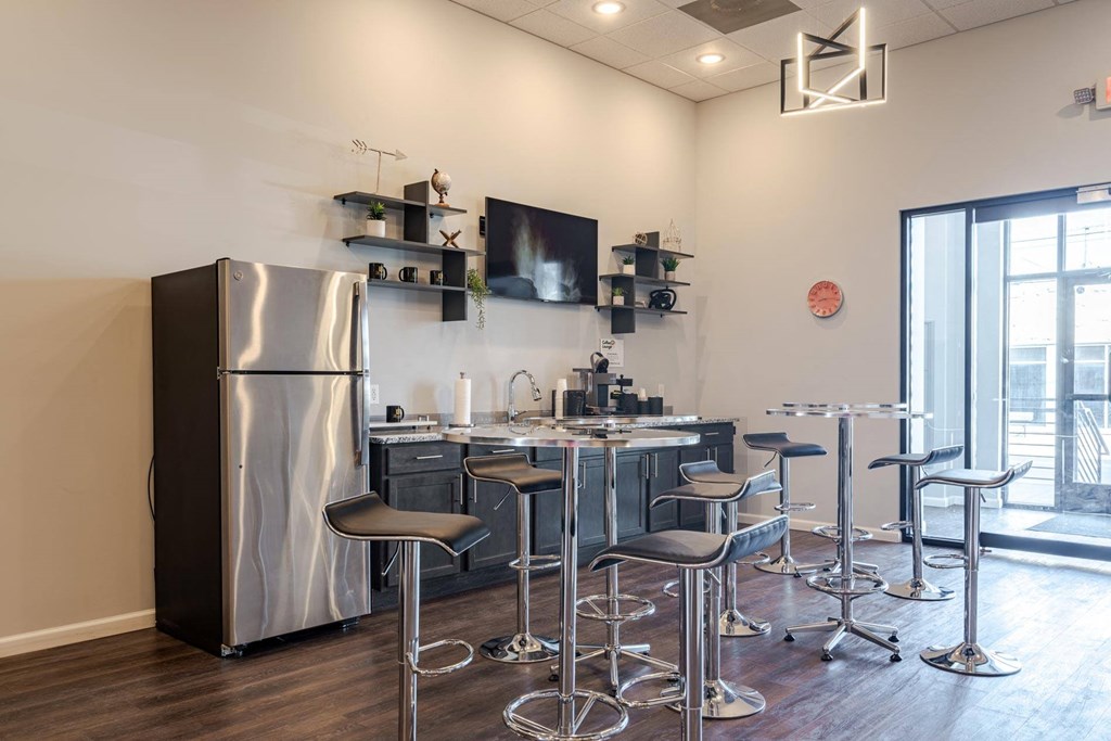 A modern kitchen with a large stainless steel refrigerator and matching bar stools.