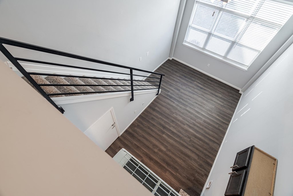 A staircase with a metal railing and wooden steps leading to a skylight.