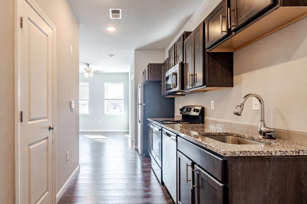 A kitchen with dark wood cabinets and a granite countertop.