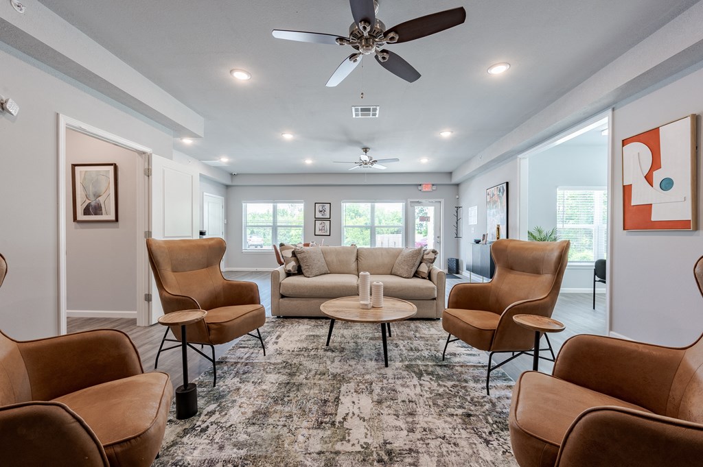 a living room with couches and chairs and a ceiling fan