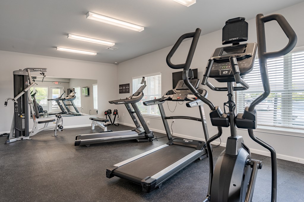 a gym with cardio equipment on the floor and a large window