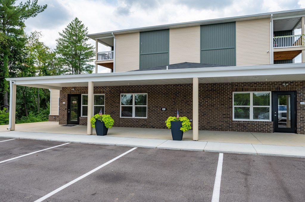 the front of a brick apartment building with a covered parking lot