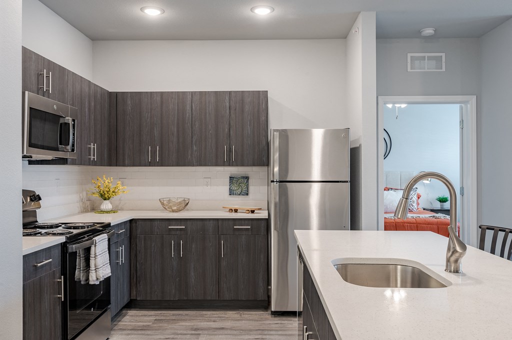 an updated kitchen with stainless steel appliances and white countertops