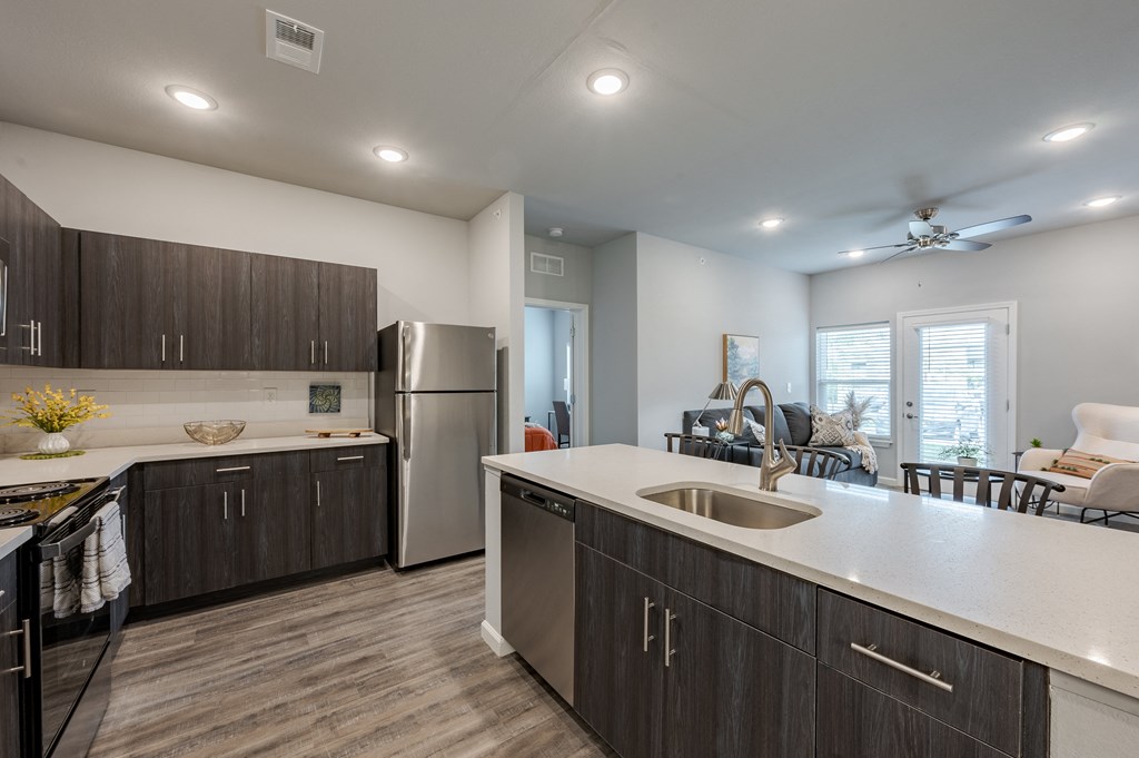 an open kitchen and living room with a stainless steel refrigerator