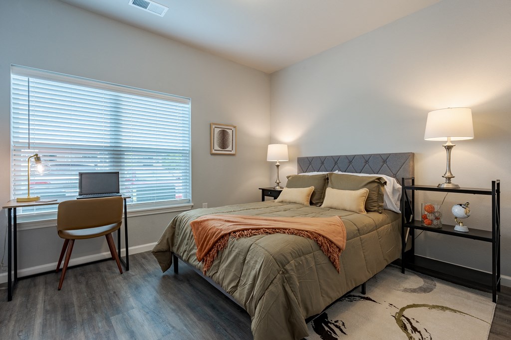 a bedroom with a bed and a desk with a laptop