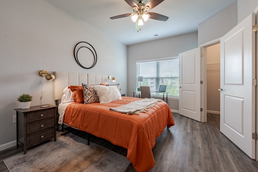 a bedroom with an orange bed and a ceiling fan