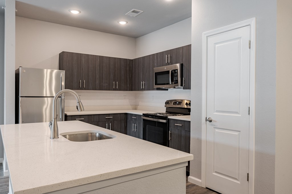 a kitchen with a white counter top and a stainless steel refrigerator